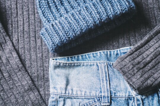 Trendy winter outfit. Gray knitted sweater, blue woolen hat and blue denim skirt