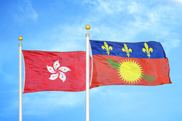 Hong Kong and Guadeloupe two flags on flagpoles and blue cloudy sky
