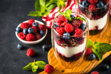 Parfait with granola, jam and fresh berries in the glass jar.