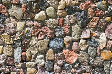 Full frame of sunlighted pebbles texture for background. Different shape natural stones stacked into a wall for decoration