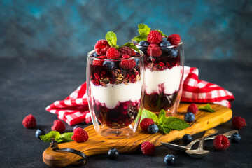 Parfait with granola, jam and fresh berries in the glass jar.