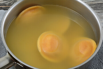 Cooked butternut squash ravioli in boiled water in stainless steel cooking pan