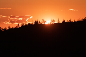 Sun setting behind the hill covered with trees in Lapland, Northern Finland during summertime. 