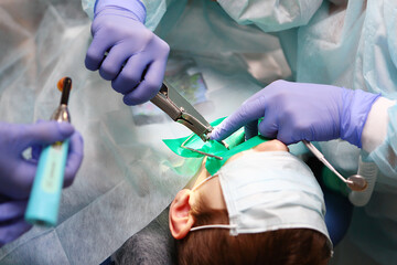 Dental surgery. A pediatric dental surgeon performs an operation to treat deep caries in a young boy.Concept of health and prevention.Copy of the space.