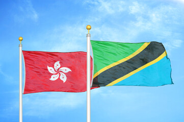 Hong Kong and Tanzania two flags on flagpoles and blue cloudy sky