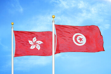 Hong Kong and Tunisia two flags on flagpoles and blue cloudy sky