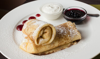 Pancake on plate with cream, flour, jam..