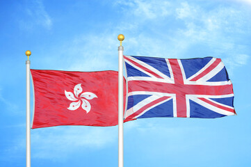 Hong Kong and United Kingdom two flags on flagpoles and blue cloudy sky