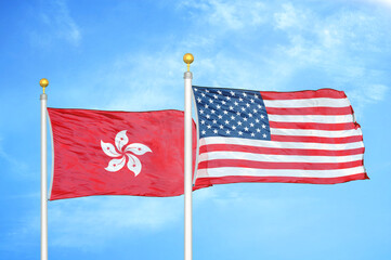 Hong Kong and United States two flags on flagpoles and blue cloudy sky