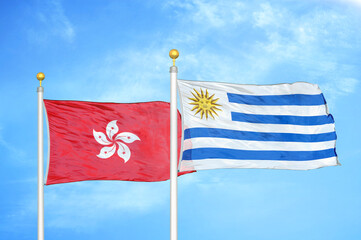Hong Kong and Uruguay two flags on flagpoles and blue cloudy sky