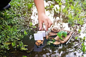 A boy plays with homemade bark boats in a stream after the rain. Children's crafts, creativity,...