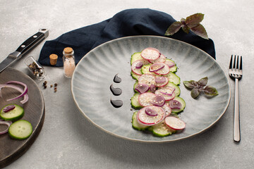 Fresh salad with radish.cucumber,red onion,sesame seeds and purple basil leaf in grey ceramic plate and ingredients.Vegan summer salad.