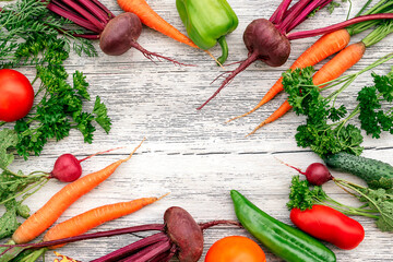 Vegetables on a white wooden background.Frame of beetroot,radish, carrot,parsley,cucumber,green bell pepper and tomatoes.Healthy diet and harvest concept.Copy space,top view,flat lay
