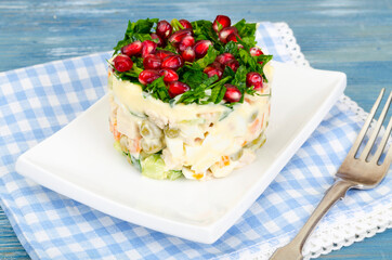 Served salad decorated with greens and pomegranate seeds.