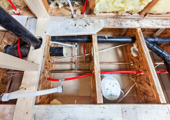 Bathroom remodel showing under floor plumbing work connecting old copper pipes to new plastic ones...