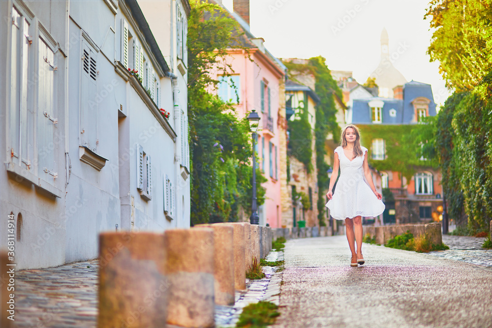 Wall mural woman in white dress walking on famous montmartre hill in paris, france at early morning