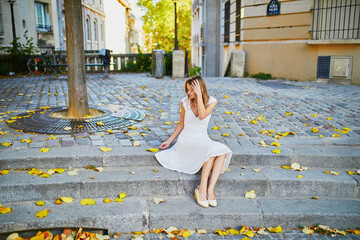 woman in white dress sitting on the stairs on famous Montmartre hill in Paris, France at early...