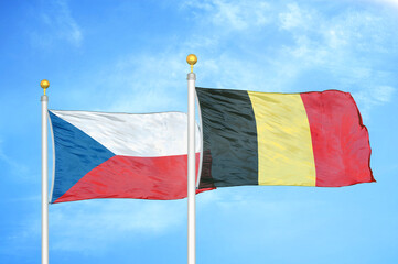 Czech and Belgium two flags on flagpoles and blue cloudy sky