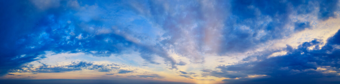 Magical Magnificent Blue Sky panorama at Cloudy sunset with sun rays and warm clouds - Ultra-wide banner.