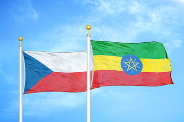Czech and Ethiopia two flags on flagpoles and blue cloudy sky