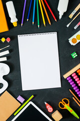 Empty sketchbook with School supplies on black board background. Back to school concept. Frame, flatlay, copy space for text. mock up