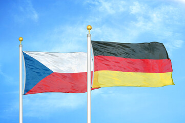Czech and Germany two flags on flagpoles and blue cloudy sky