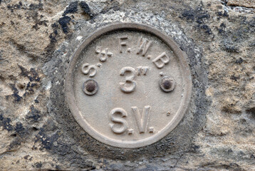 Close Up Detail of Old Cast Iron Identity Plate on Rustic Textured Stone Wall 
