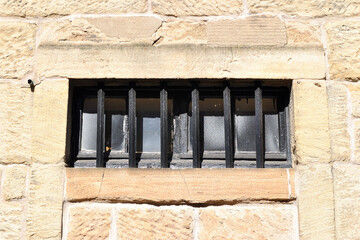 Close Up of Small Window with Iron Bars in Textured Stone Wall