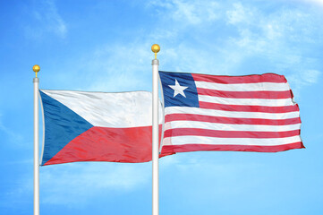 Czech and Liberia two flags on flagpoles and blue cloudy sky