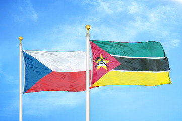 Czech and Mozambique two flags on flagpoles and blue cloudy sky