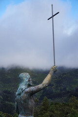 Statue of Jesus Christ holding a Cross against a cloudy sky