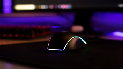 Computer mouse with neon illumination on a white glossy table, dark room, neon light, diodes. Gaming devices, neon lights, white glossy table. Lifestyle, game zone.