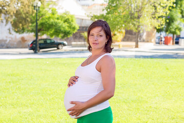 Close up of pregnant belly in nature in a city park