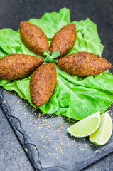 Delicious Lebanese  food, kibbeh (kibe) on black slate stone and granite background.