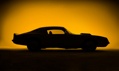 Fototapeta na wymiar Silhouette of an old fashion muscle car on a yellow background.