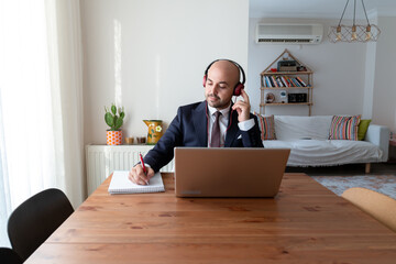 Businessman taking notes in his home office, listening to music, working. manager manager working remotely.