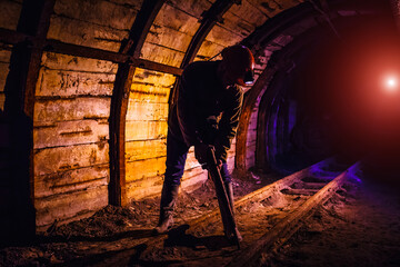 Fototapeta premium Miner working a jackhammer in a coal mine. Work in a coal mine. Portrait of a miner. Copy space.