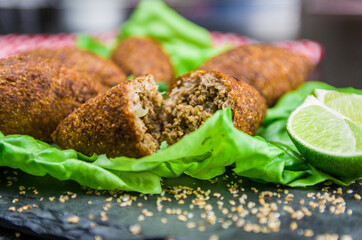 Delicious Lebanese  food, kibbeh (kibe) with sauces and lemon on black slate stone and granite background with traditional keffyeh. - 368123768
