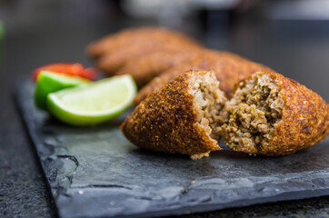 Delicious Lebanese  food, kibbeh (kibe) on black slate stone and granite background.