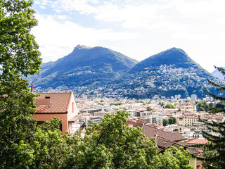 Fototapeta na wymiar Aerial view of Lugano city with houses and cityscape, and alpine Swiss mountains