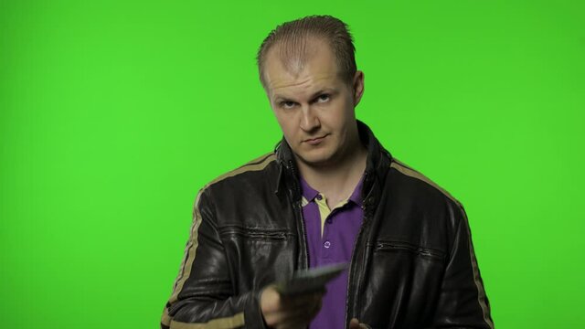 Rocker man employee take money dollar cash banknotes out of his pocket and offers them to the camera