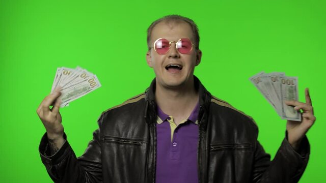 Excited happy lottery winner, glad rocker man dance and celebrate win. Hold money cash on his hands