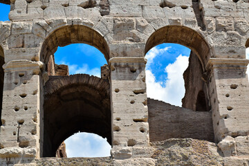 Detail of the famous Italian Colosseum monument in Rome, built in marble, with a blue sky background