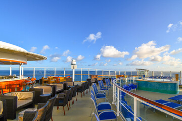 An empty bar lounge on the upper deck of a cruise ship at sea.
