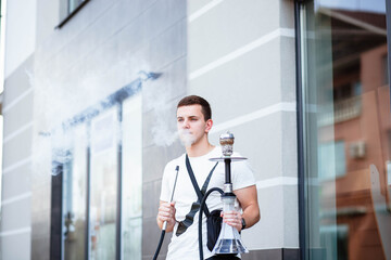 Young handsome guy smoking hookah alone closeup. Young guy smoking a hookah. Hookah and sparks from coals. Shisha, spark, hookah sparks. Young man smokes a fragrant oriental hookah.