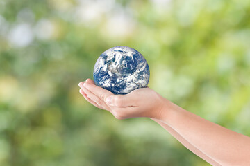 Environment day concept: Hand holding earth globe over blurred nature background. Elements of this image furnished by NASA