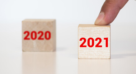 Happy New Year 2021 wood cube blocks and leaving the Year 2020 represented by 0 behind to be forgotten in the background. Bokeh Christmas holiday theme with copy space.
