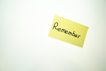 Yellow sticker with the word remember on a white wall. 