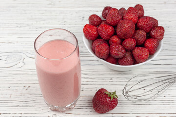 strawberry cocktail, blender and plate with strawberries on a white wooden background