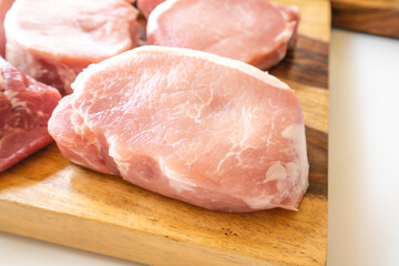 Boneless raw pork loin chops close up on wooden cutting board